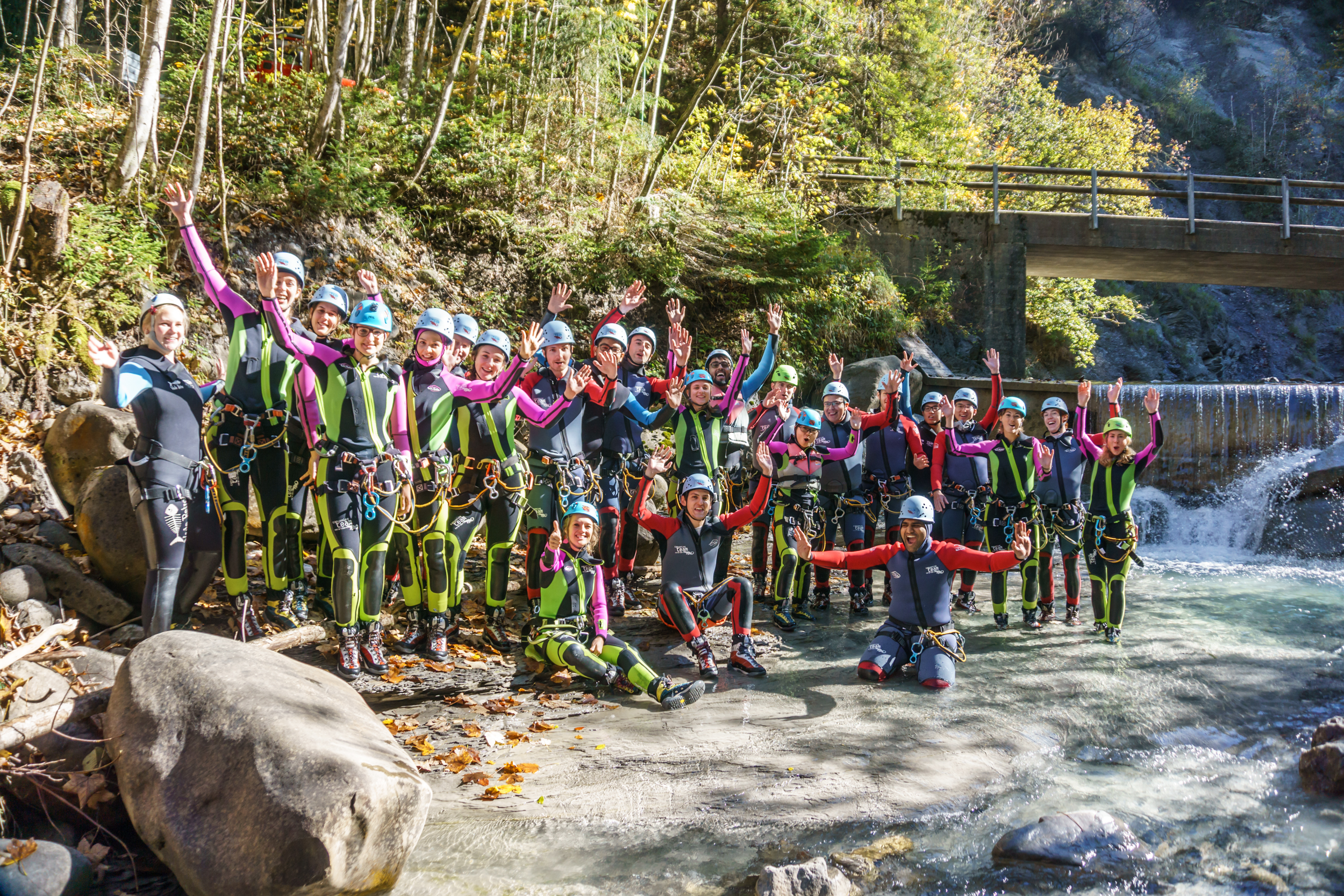 Canyoning-Gruppe in Ausrüstung vor einem Wasserfall