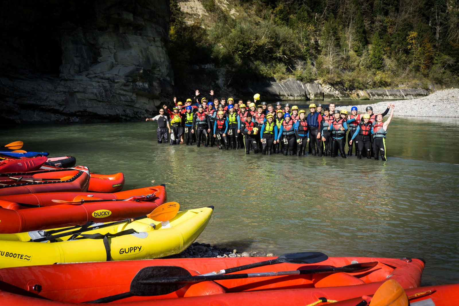 1. Große Rafting-Gruppe mit bunten Booten an einem Fluss