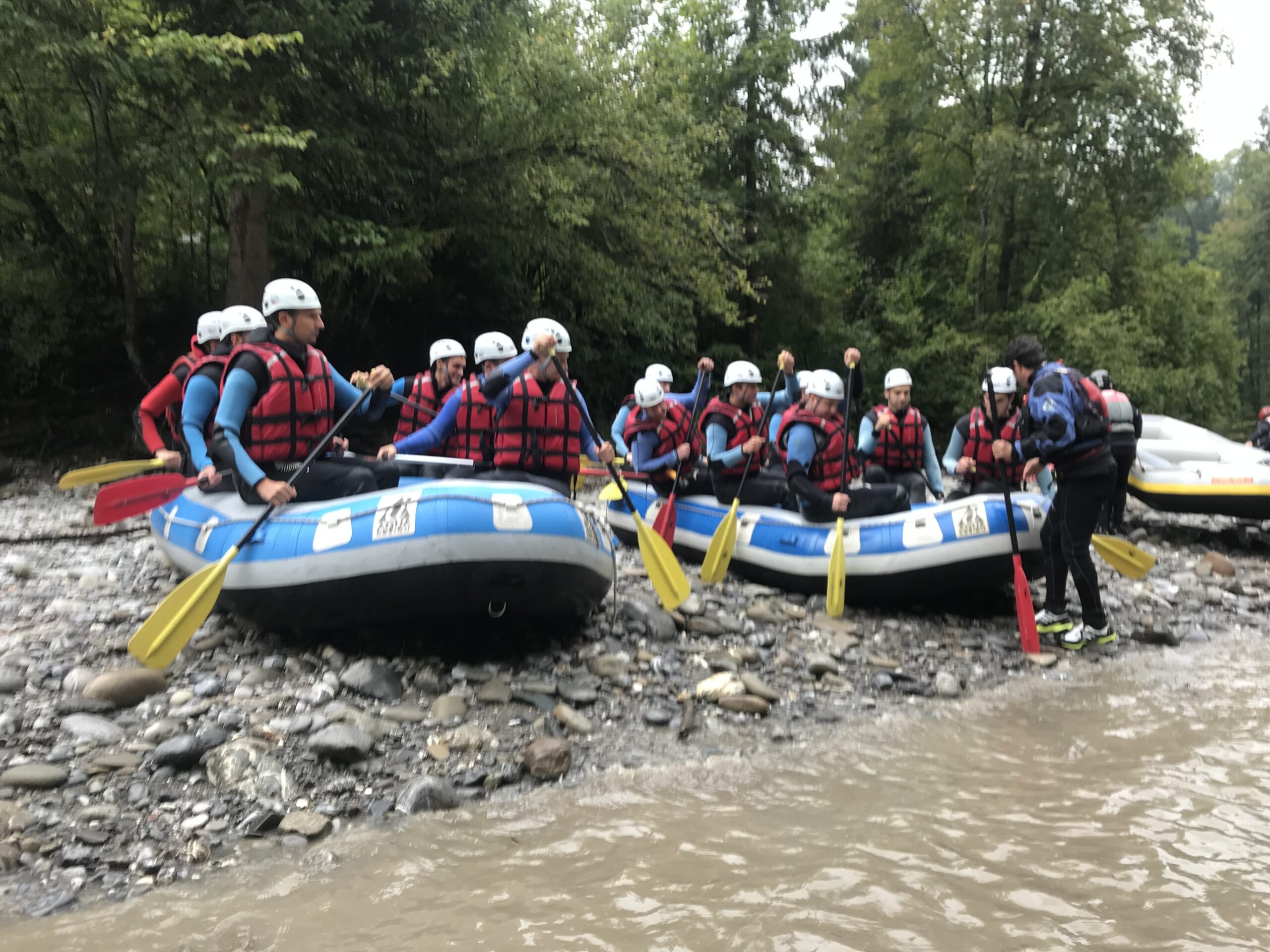 Rafting-Gruppe mit Schlauchbooten am Flussufer