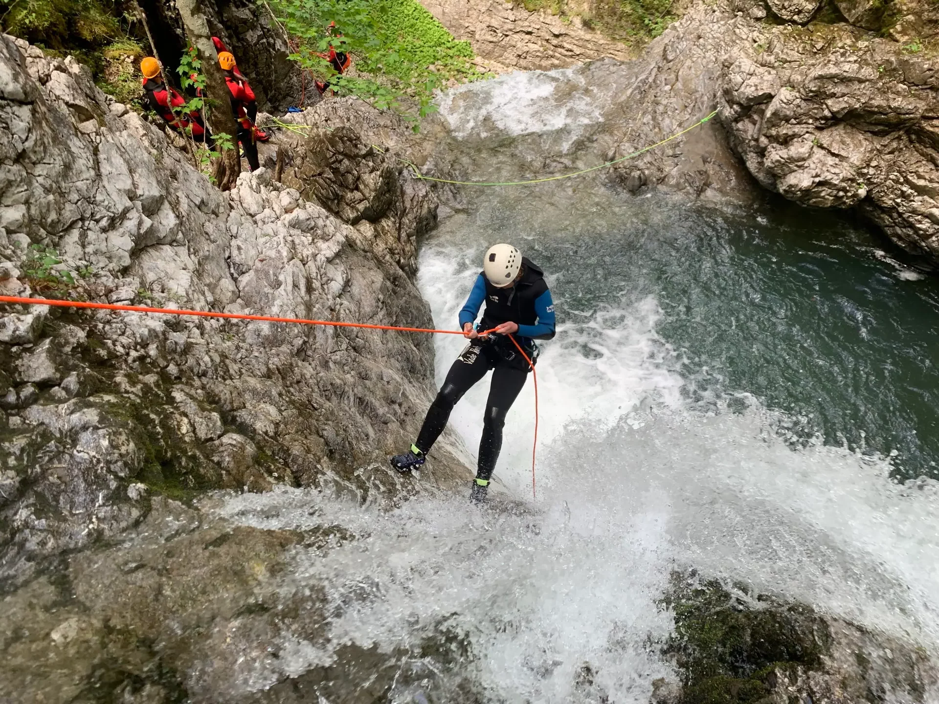 Person beim Abseilen an einem Wasserfall mit einer kleinen Canyoning-Gruppe