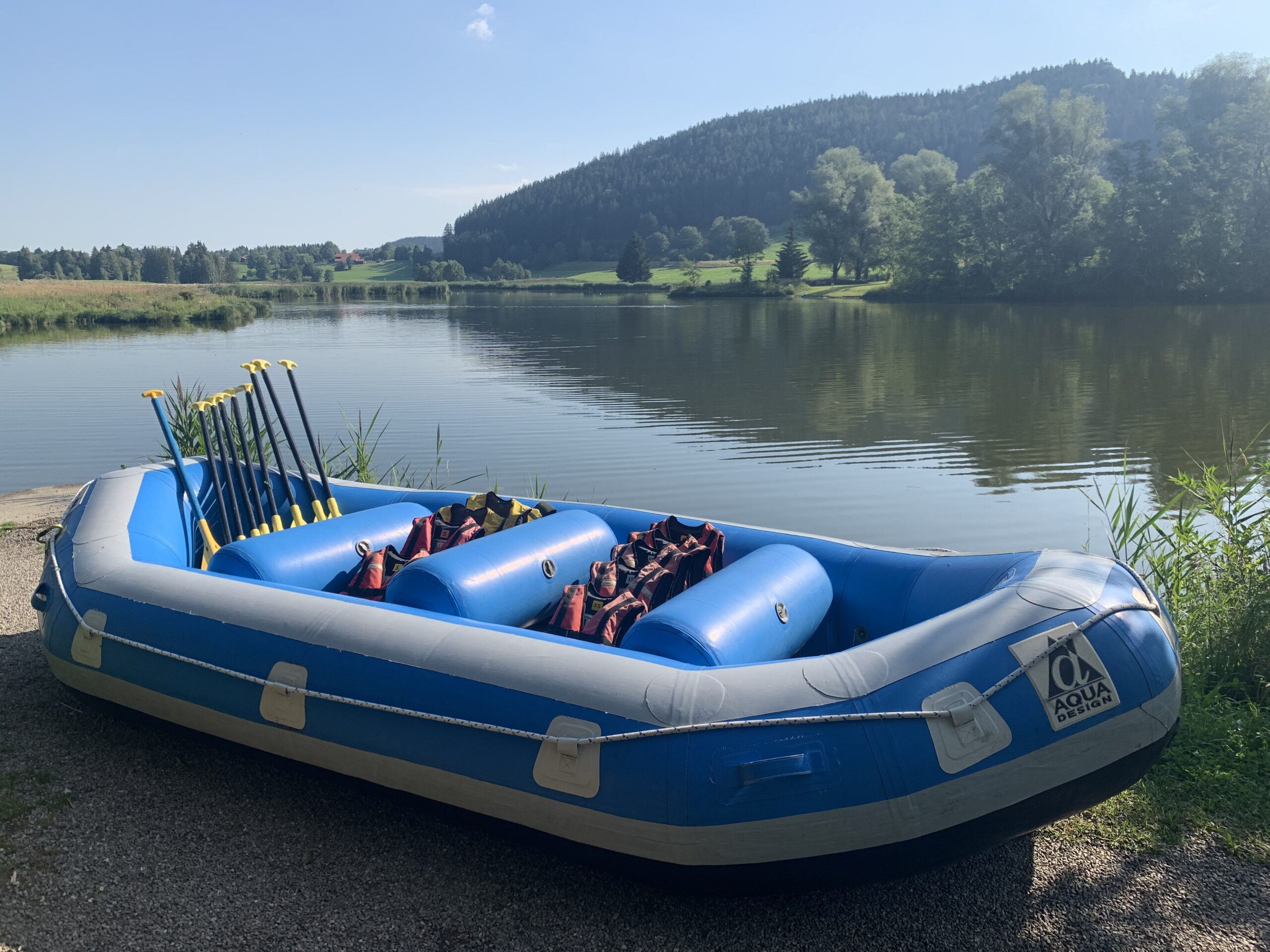 Rafting-Boot mit Paddeln und Schwimmwesten am Ufer vor dem Tourstart