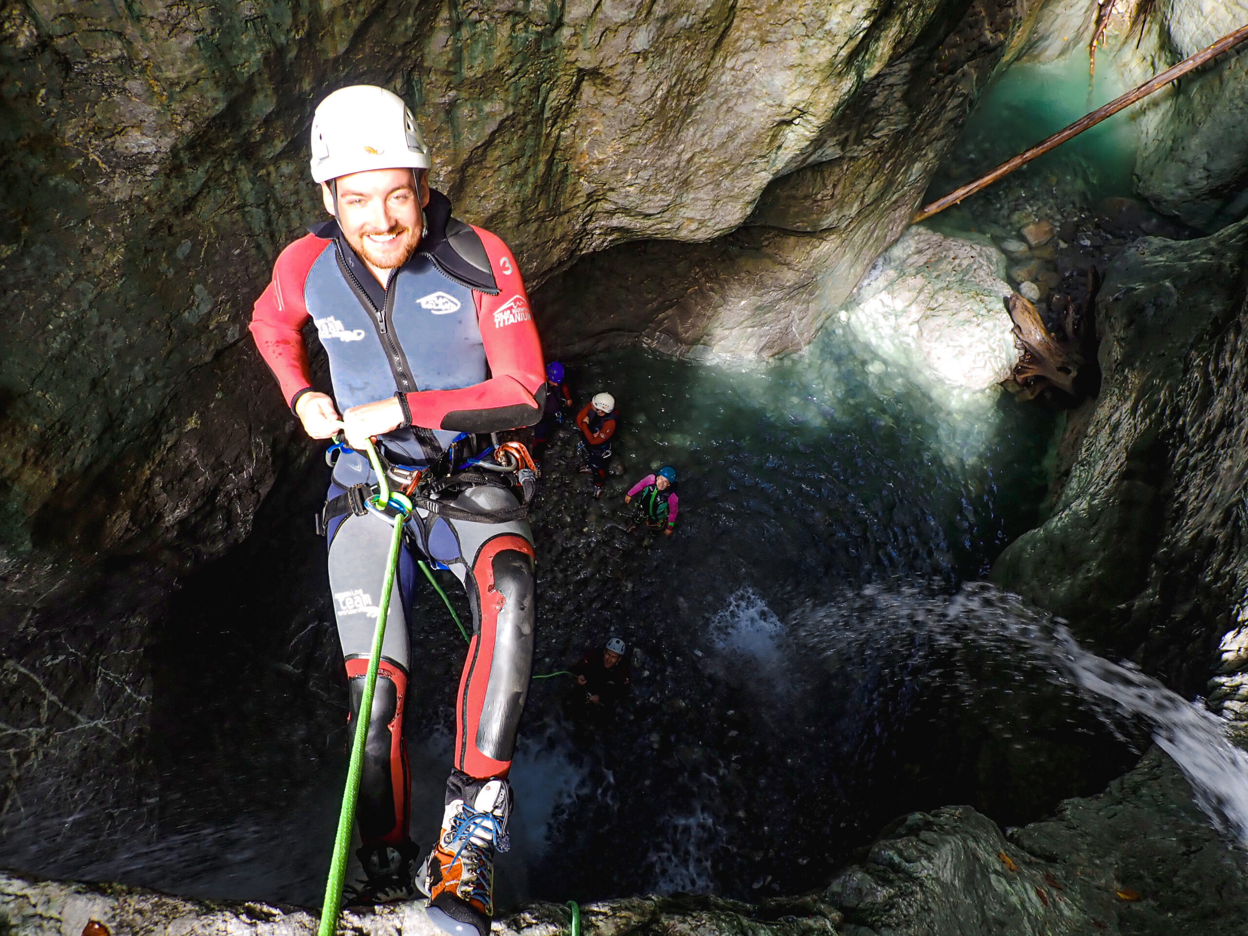 Mann beim Abseilen über einem Wasserbecken in einer Schlucht
